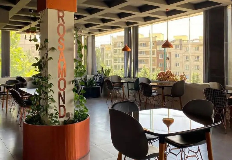 فضای داخلی مدرن و روشن رستوران و کافه رزاموند با منظره زیبای شهر، دکوراسیون شیک و گیاهان سرسبز، محیطی دلنشین برای صرف غذا و نوشیدنی.