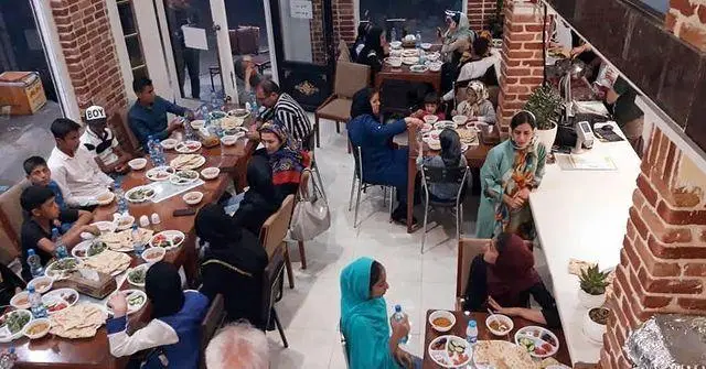 تصویری از مشتریان پرشور و خانواده‌ها در حال صرف غذا در فضای داخلی شلوغ و دلپذیر فست فود فارسیز، ارائه‌دهنده غذای باکیفیت.