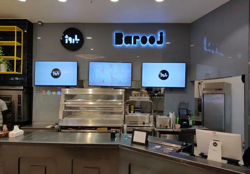 فضای داخلی و پیشخوان مدرن رستوران فست فود باروژ با تابلوهای نورانی Barooj و نمایشگرهای منو برای سرویس دهی سریع غذا.