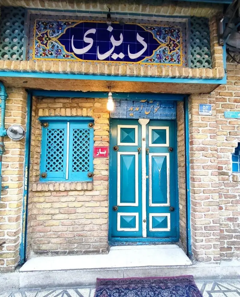 نمای ورودی دلنشین رستوران سنتی دیزی سرا، با معماری آجری، درب و پنجره های آبی فیروزه ای. تجربه غذای اصیل ایرانی.