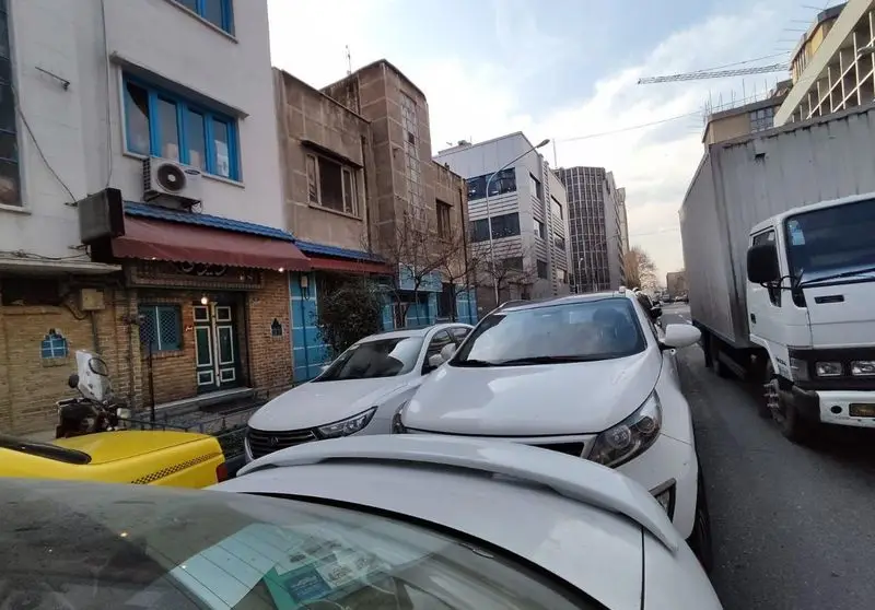 نمای بیرونی شلوغ رستوران دیزی سرای تهران در خیابان، با ماشین‌های پارک شده و معماری سنتی ایرانی برای غذای دیزی.