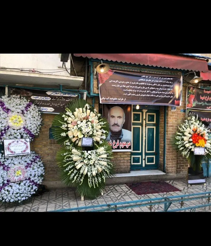 مراسم ترحیم و بنر تسلیت در ورودی رستوران دیزی سرا، همراه با تاج گل‌های بزرگ در فضای شهری