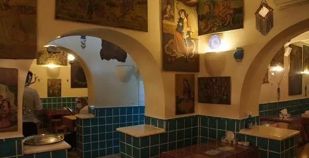 فضای داخلی رستوران دیزی سرا: دکور سنتی ایرانی با طاق‌های زیبا، نقاشی‌های نفیس دیواری و کاشی‌کاری سبز. تجربه‌ای دلنشین از غذاهای اصیل ایرانی.