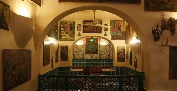 فضای داخلی دنج و سنتی رستوران دیزی سرا با معماری طاقی، کاشی‌کاری سبز و نقاشی‌های زیبا، آماده پذیرایی از میهمانان.