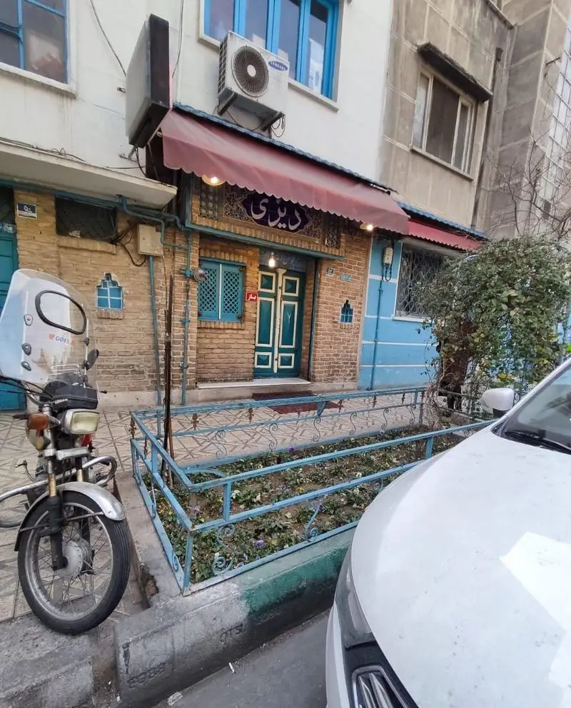 نمای بیرونی رستوران دیزی سرا با آجرکاری سنتی، در و پنجره‌های آبی و تابلوی «دیزی سرا» در خیابان، ارائه‌دهنده غذای سنتی ایرانی.
