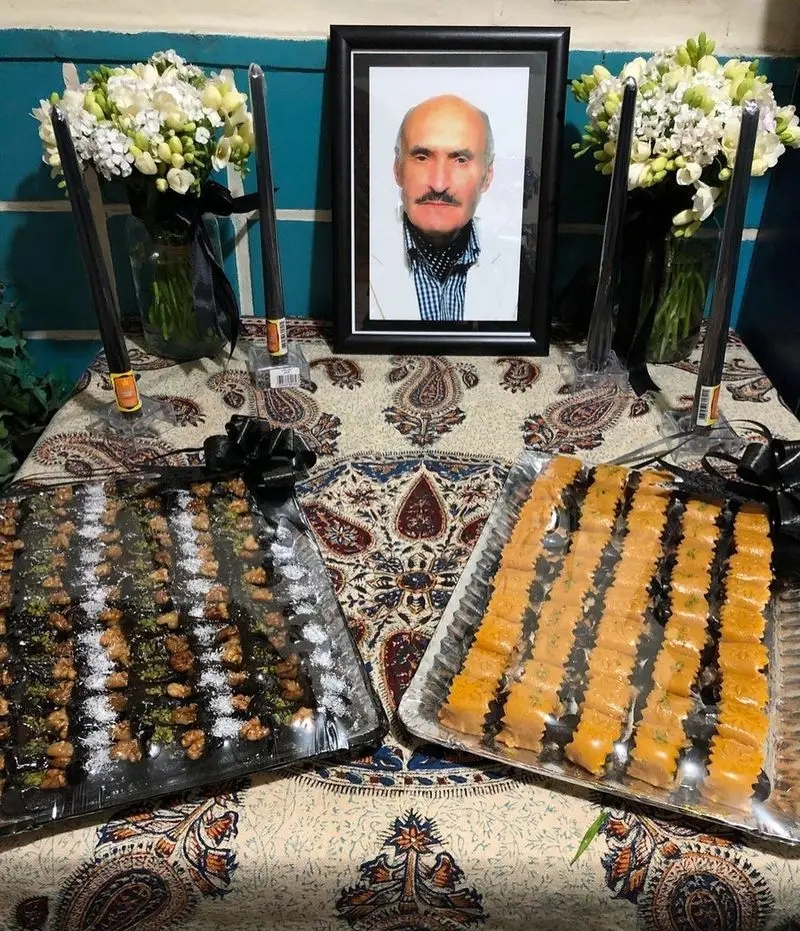 میز یادبود سنتی در رستوران دیزی سرا با عکس، گل، شمع و سینی‌های حلوا و شیرینی‌های پذیرایی مراسم.