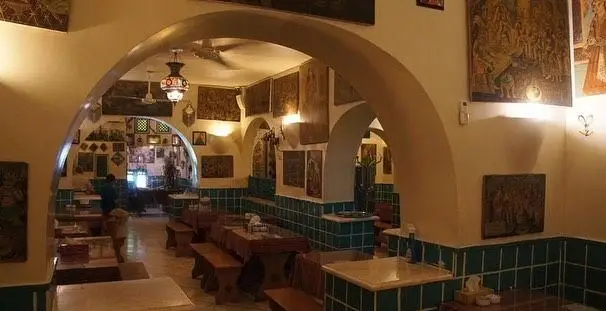 فضای داخلی دنج و سنتی رستوران دیزی سرا با طاق‌های زیبا، دیوارهای کاشی‌کاری شده و نقاشی‌های قدیمی. میز و نیمکت چوبی.