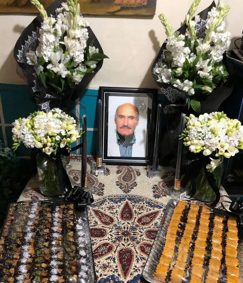 پذیرایی از میهمانان در مراسم یادبود رستوران دیزی سرا؛ میز مملو از گل‌های سفید، شمع و سینی‌های شیرینی و دسر.