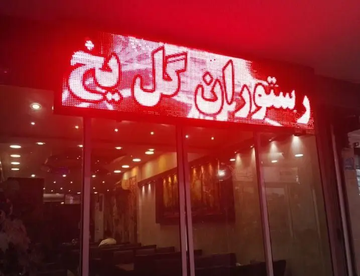 تابلوی LED درخشان رستوران گل یخ با حروف سفید و نور قرمز در بالای ورودی شیشه‌ای، نشان‌دهنده یک تجربه غذایی دلپذیر و محیطی آرام برای مشتریان