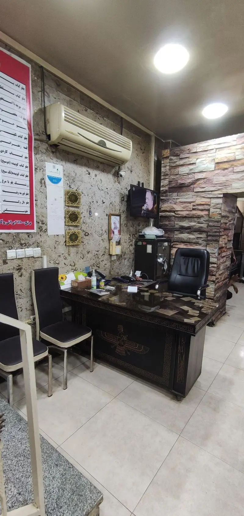 دکوراسیون داخلی و فضای پذیرایی مشتریان در رستوران ناب، با میز مدیریت دارای نقش Faravahar، منو و دیوارپوش سنگی.