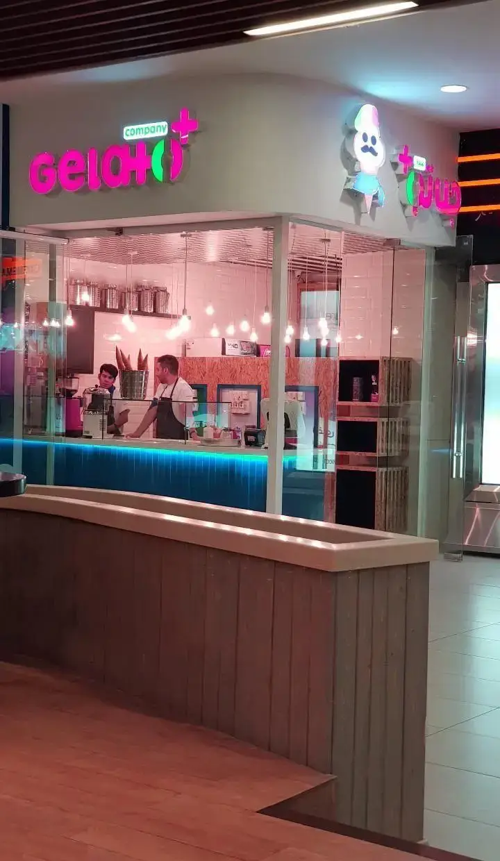 یک بستنی فروشی مدرن و جذاب ژلاتو کمپانی پلاس در مجتمع تجاری ارگ، با تابلوهای نئونی صورتی و سبز و فضای داخلی روشن.