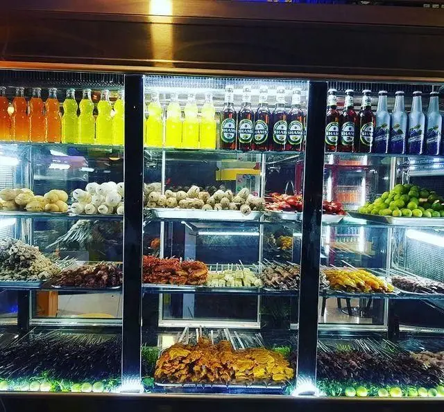 ویترین پر از کباب جگرسرای لیموترش شامل سیخ‌های جگر، دل، قلوه، جوجه و قارچ، همراه با انواع نوشیدنی‌های خنک و لیموترش تازه.