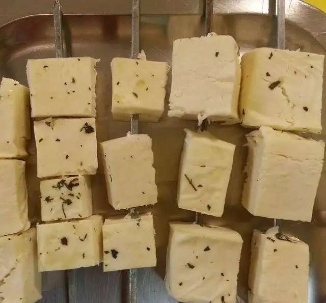 جگرسرای لیموترش: سیخ‌های پنیر کبابی با تکه‌های پنیر تازه مکعبی و سبزیجات معطر، آماده برای پخت و سرو در محیطی دلنشین.