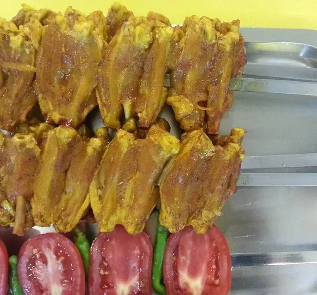 سیخ‌های کباب جگر، دل و قلوه مرینیت شده طلایی رنگ با گوجه و فلفل تازه. لذت طعم اصیل در جگرسرای لیموترش.