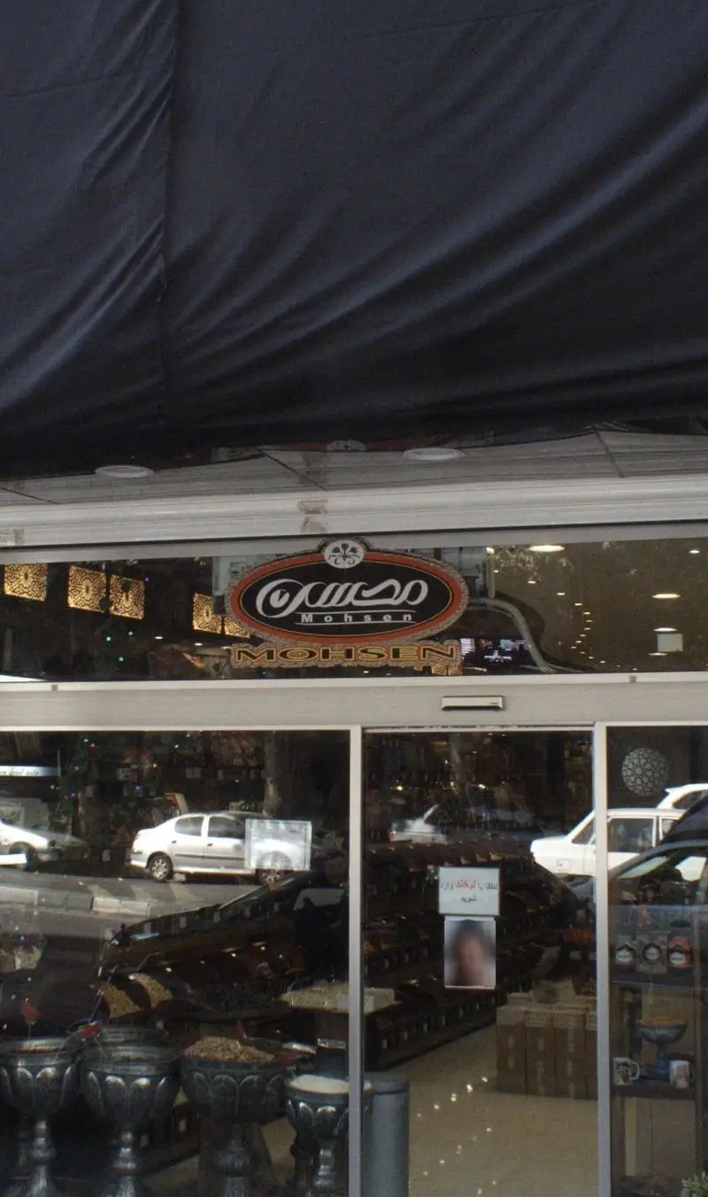 تصویر نمای بیرونی مغازه خشکبار محسن با تابلوی مشخص "Mohsen". از پشت شیشه‌ها، آجیل و خشکبار تازه و متنوع موجود در داخل فروشگاه مشخص است.