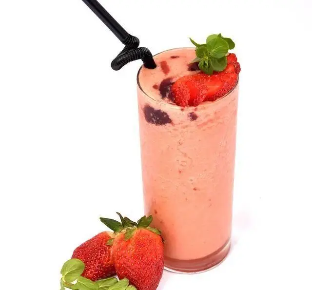 اسموتی توت فرنگی تازه و خوشمزه در لیوان بلند، نوشیدنی خنک و تابستانی مناسب رستوران و کافی شاپ دورهمی با تزئین نعناع و توت فرنگی.