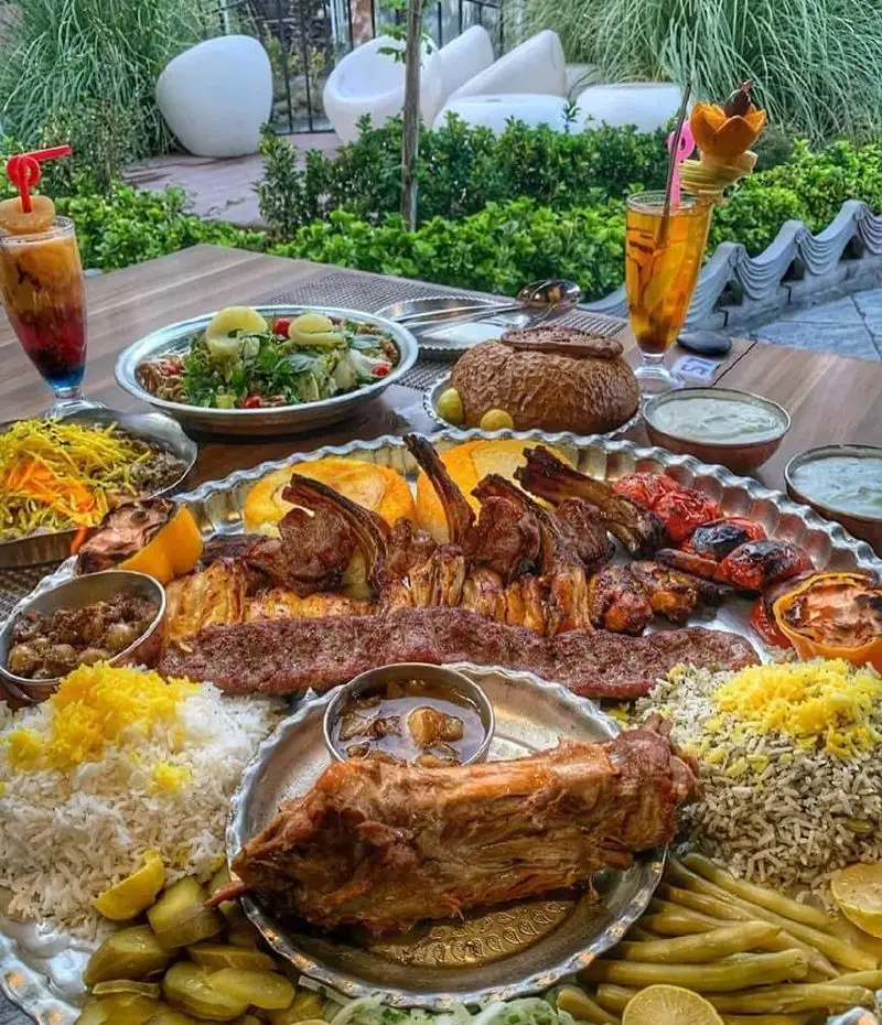 سفره رنگین رستوران دورهمی: انواع کباب (شیشلیک، کوبیده)، باقالی پلو، برنج زعفرانی، خورش، سالاد و نوشیدنی در فضای سبز دلنشین. تجربه غذای اصیل ایرانی.