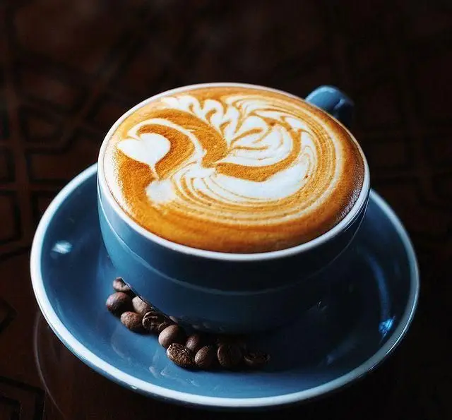 زیبایی یک فنجان لاته داغ با لاته آرت هنرمندانه و دانه های قهوه در کافی شاپ و رستوران دورهمی. لحظاتی خوش را با ما تجربه کنید.