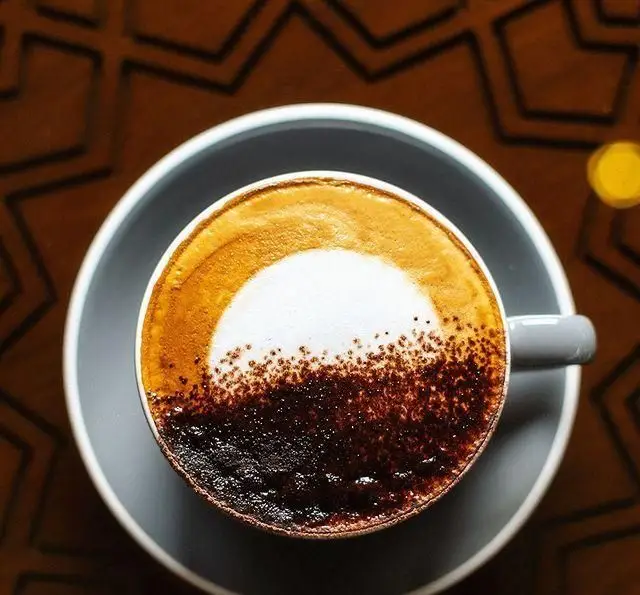 یک فنجان قهوه لاته/کاپوچینوی زیبا با طراحی خاص لاته آرت، آماده سرو در رستوران و کافی شاپ دورهمی. لذت یک نوشیدنی گرم.