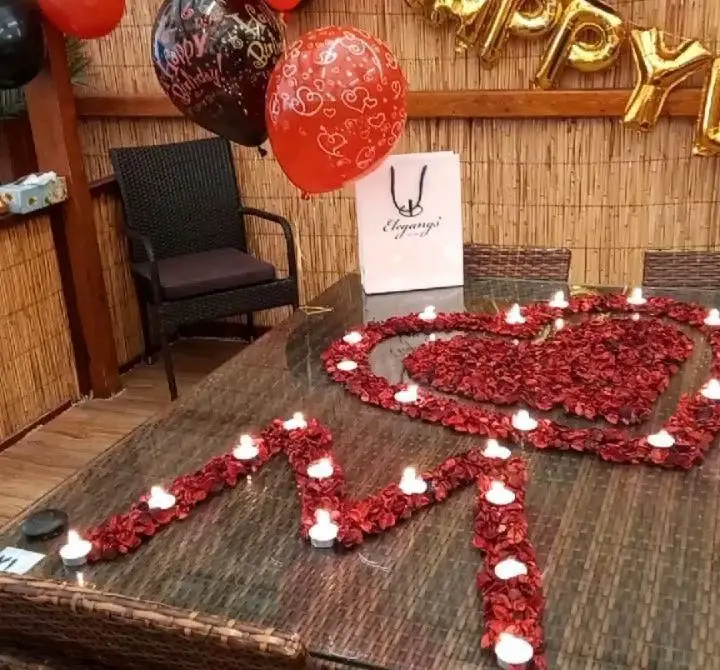 چیدمان میز شام رمانتیک با قلب گلبرگ و شمع در رستوران و کافی شاپ دورهمی، فضایی خاص برای جشن تولد و سالگرد.