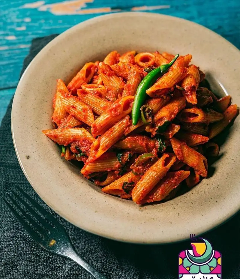 پاستا پنه داغ و لذیذ با سس قرمز و فلفل سبز تازه، سرو شده در رستوران و کافی شاپ دورهمی. غذایی خوش‌طعم و جذاب برای دورهمی.