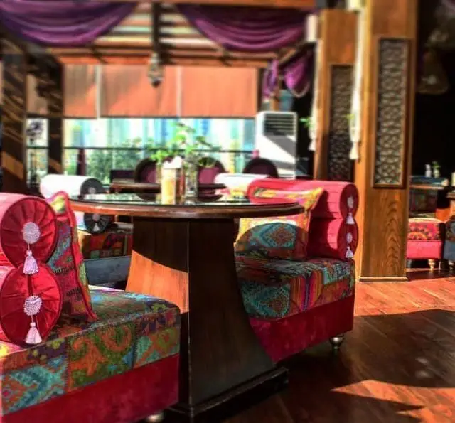 فضای داخلی دنج و دلنشین رستوران و کافی شاپ دورهمی با مبلمان رنگارنگ و میز چوبی، مکانی عالی برای دورهمی دوستانه.