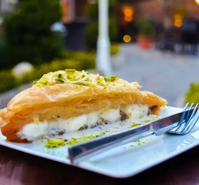 یک برش باقلوای خوشمزه پر شده با بستنی یا خامه همراه با پسته. تجربه‌ای شیرین در رستوران و کافی شاپ دورهمی.