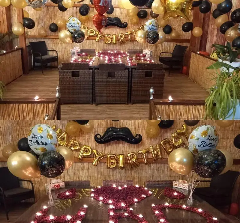 فضای تولد رستوران و کافی شاپ دورهمی: تزیینات لوکس با بادکنک‌های طلایی، مشکی و سبیل، میزهای شمع‌آرایی شده با گلبرگ، فضایی دنج و رمانتیک برای جشن‌ها