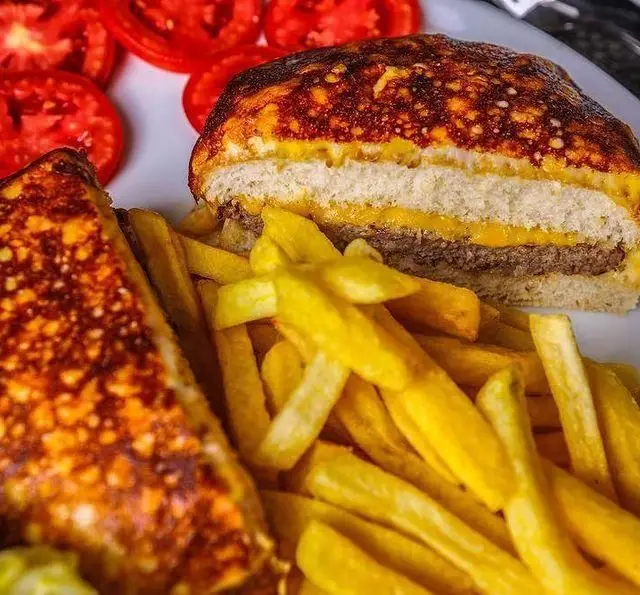 همبرگر دوبل پنیر، ساندویچ گریل و سیب زمینی سرخ کرده طلایی در رستوران و کافی شاپ دورهمی. غذای لذیذ برای ناهار یا شام.