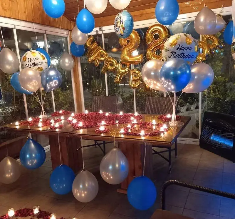 دکوراسیون باشکوه جشن تولد 22 سالگی در رستوران و کافی شاپ دورهمی با بادکنک‌های رنگی، گلبرگ و شمع.