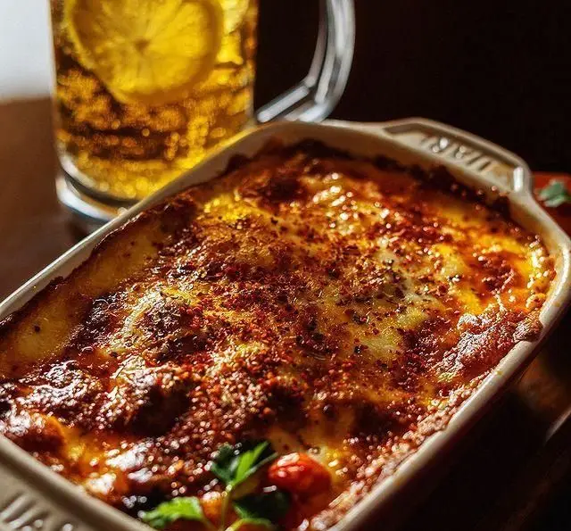 غذای خوشمزه و داغ لازانیا یا گراتن در رستوران و کافی شاپ دورهمی. غذای فرنگی خوش پخت با نوشیدنی لیمو ترش تازه.