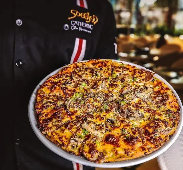 تصویری از پیتزای داغ و تازه قارچ و پنیر رستوران دورهمی، با پنیر طلایی و سبزیجات سبز، آماده سرو توسط سرآشپز ماهر.