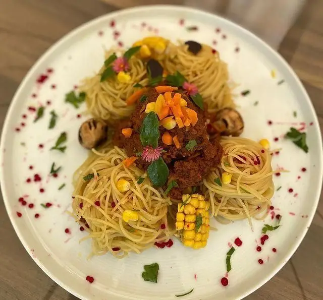 بشقاب زیبای اسپاگتی با سس گوشت، ذرت و قارچ در رستوران و کافی شاپ دورهمی؛ غذای خوشمزه و خاص برای مشتریان.