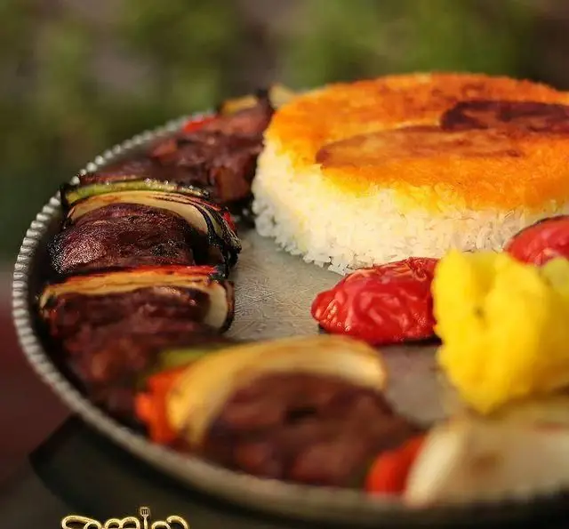 بشقاب کباب لذیذ با پیاز و فلفل در کنار برنج قالبی زعفرانی در رستوران دورهمی. بهترین انتخاب برای یک ناهار یا شام خوشمزه.