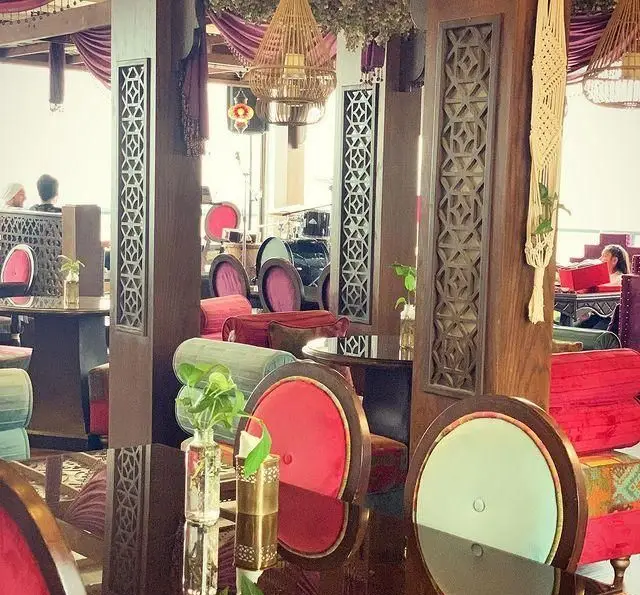 فضای داخلی دلنشین و شیک رستوران و کافی شاپ دورهمی با صندلی‌های رنگارنگ مخملی، میزهای چوبی براق و دکوراسیون تلفیقی سنتی و مدرن جذاب.