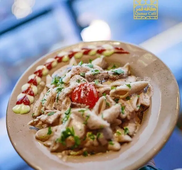 پاستا پنه مرغ با سس سفید و گوجه گیلاسی، تزئین شده با سس‌های رنگی، یک غذای اشتهاآور از رستوران و کافی شاپ دورهمی.