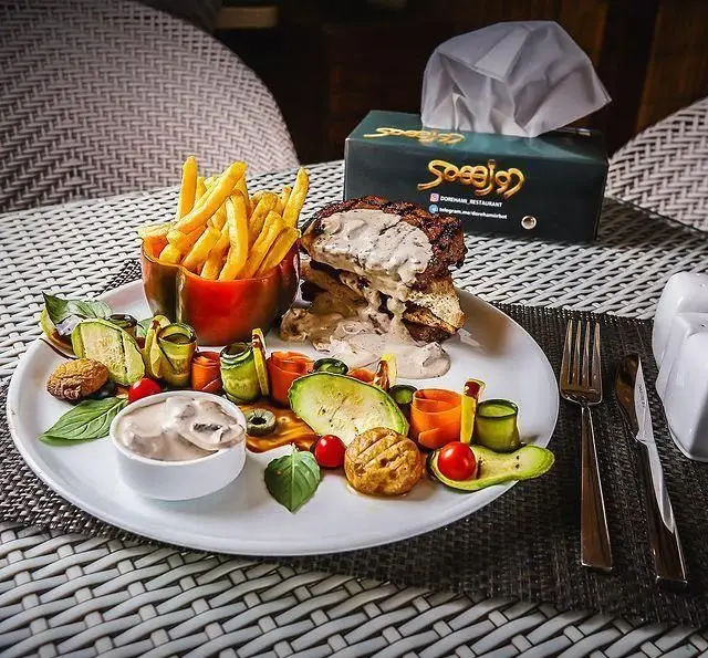 رستوران و کافی شاپ دورهمی: غذایی لذیذ و متنوع شامل برگر مخصوص، سیب زمینی سرخ کرده و سبزیجات تازه، در محیطی دلنشین برای مشتریان.