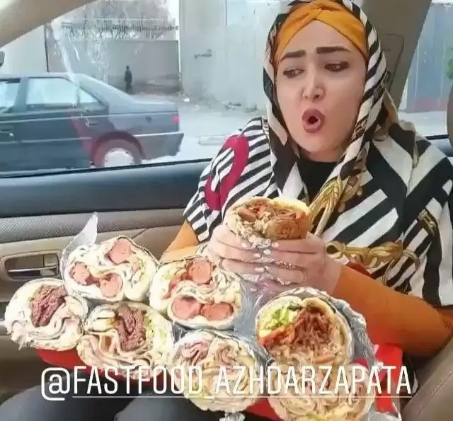 زن با ساندویچ‌های زاپاتای فست فود اژدر زاپاتا در خودرو، آماده برای خوردن یک غذای لذیذ و بسیار حجیم.