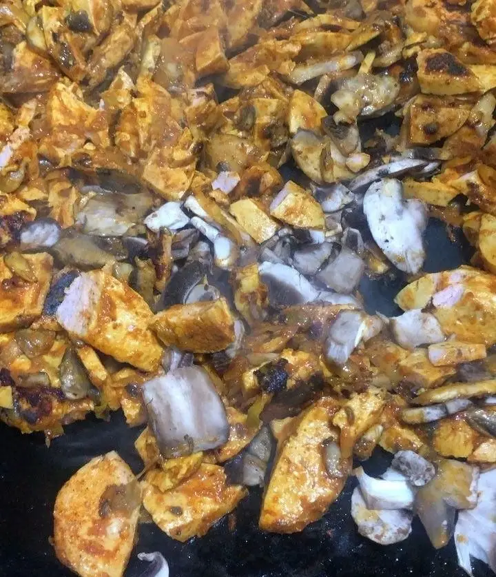 طبخ ساندویچ مرغ و قارچ مخصوص فست فود اژدر زاپاتا: تکه‌های مرغ و قارچ بر روی گریل، آماده برای یک وعده خوش طعم.