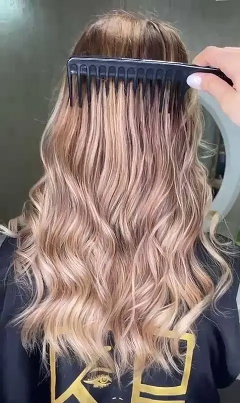 شانه کردن موهای بلند حالت دار با رنگ موی بلوند دودی و صورتی ملایم با شانه دندانه درشت در سالن زیبایی و آرایشگاه زنانه