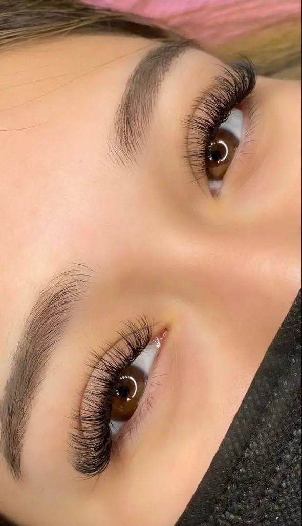 نمای نزدیک از کاشت و اکستنشن مژه والیوم پرپشت روی چشمان قهوه‌ای در بخش تخصصی آرایش چشم سالن زیبایی پانیذ خانی