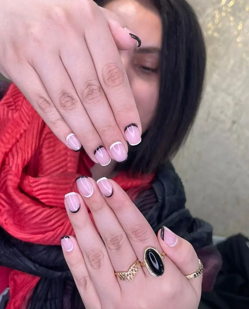 طراحی ناخن فرنچ دخترانه با ترکیب رنگ مشکی و سفید بسیار شیک و مدرن به همراه انگشترهای طلایی زیبا در سالن تخصصی کاشت ناخن