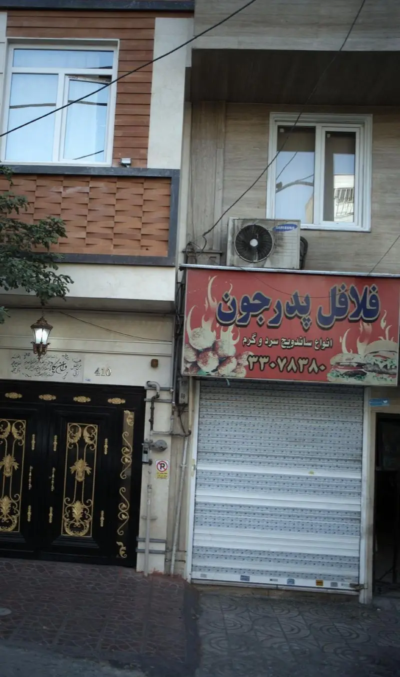 تصویر کسب و کار فلافل پدر جون، تابلوی قرمز با طرح شعله و فلافل، ساندویچ برگر و شماره تماس ۳۳۰۷۸۳۸۰. متخصص ساندویچ گرم و سرد.