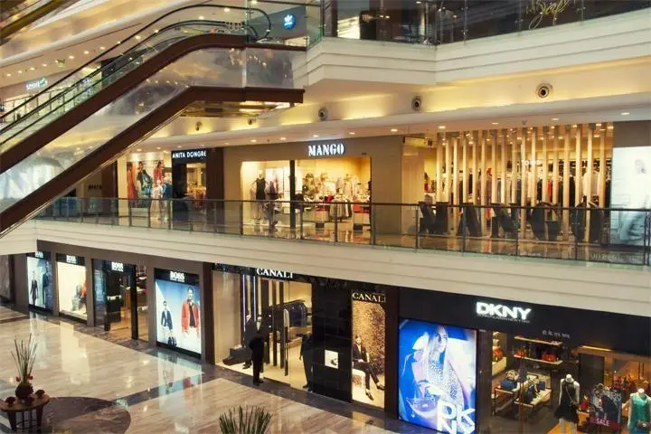 فضای داخلی مرکز خرید پالادیوم: نمایش طبقات، پله برقی و فروشگاه‌های برندهای معتبر جهانی مانند MANGO و DKNY.