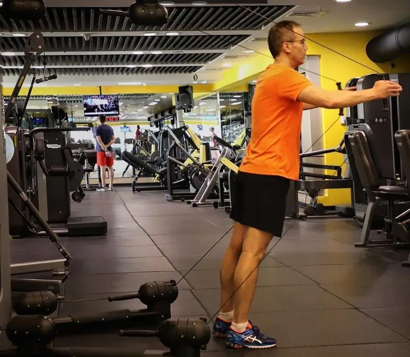 مردی در حال ورزش با دستگاه سیم کش در باشگاه ورزشی مجهز مرکز خرید پالادیوم تهران برای آمادگی جسمانی و تندرستی.