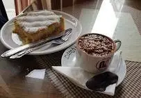 میز صبحانه یا عصرانه دلپذیر در کافه قنادی اوریانت: کیک تازه پخته شده با پودر شکر و یک فنجان شکلات داغ با مغز پسته و شکلات.