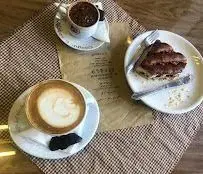 تصویری از میز کافه قنادی اوریانت: لاته و قهوه تازه، همراه با کروسان شکلاتی لذیذ. بهترین مکان برای صبحانه و دسر.