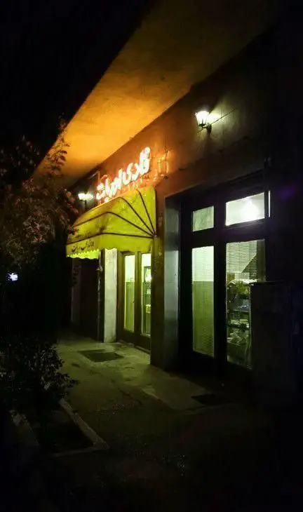 نمای بیرونی کافه قنادی اوریانت در شب با تابلوی درخشان و سایبان زرد، ورودی دنج و روشن برای تجربه دلپذیر شیرینی و قهوه.