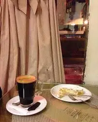 قهوه خوش‌عطر با کرمای طلایی و برش کیک لذیذ در کافه قنادی اوریانت. فضایی دنج و دلنشین برای تجربه بهترین طعم‌ها.