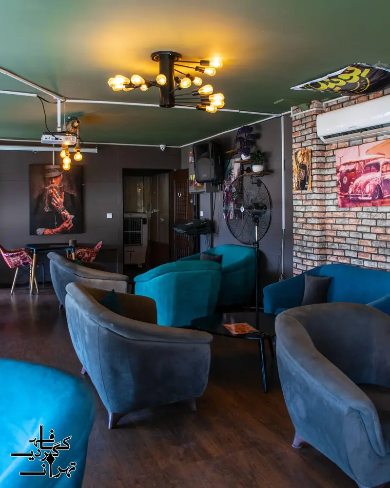 تصویری از فضای داخلی کافه یونیس با دکوراسیون مدرن و شیک. مبلمان راحتی خاکستری و آبی، لوستر منحصر به فرد و محیطی دنج و آرام برای گذراندن وقت.